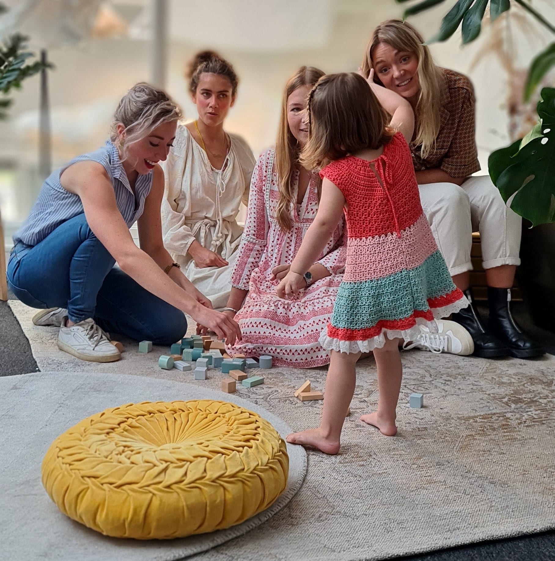 Looking for babysitting jobs? Look no further! In this image you see four girls having fun with a cute toddler and a yellow cushion on the ground