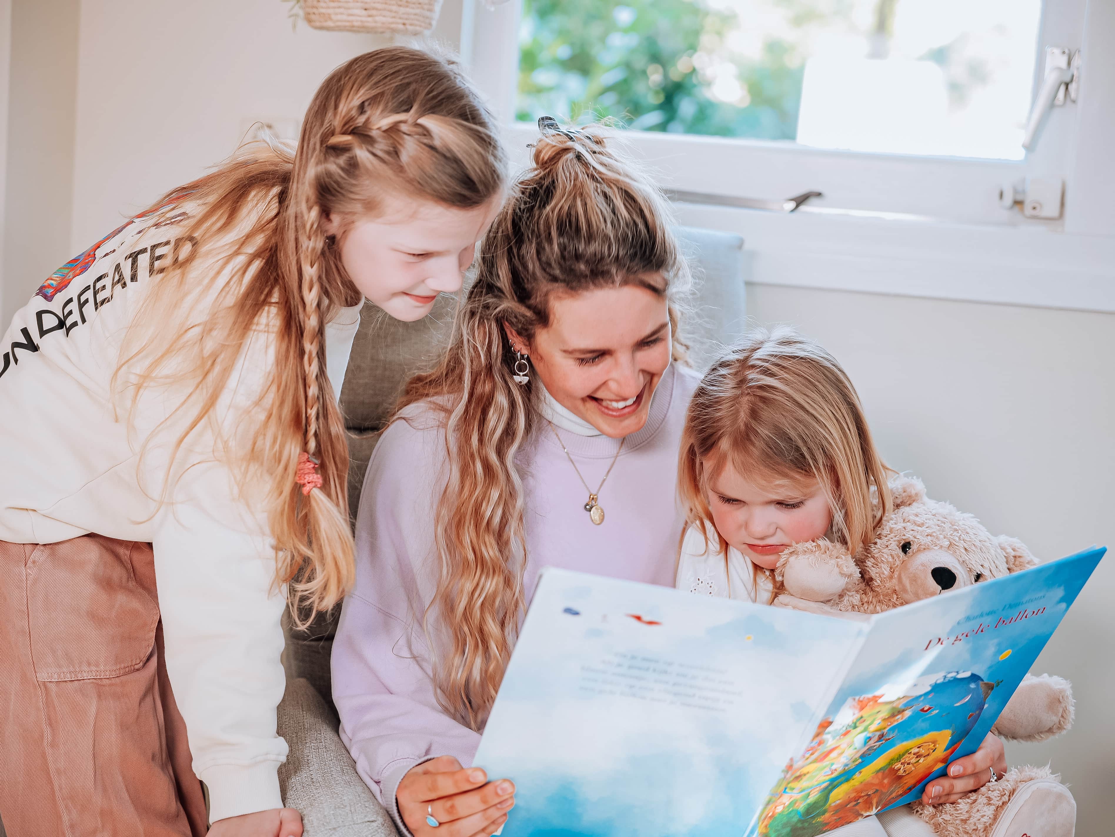 Book a babysitter or more information about babysitting like this cute woman reading two cute kids from a book about finding the yellow balloon