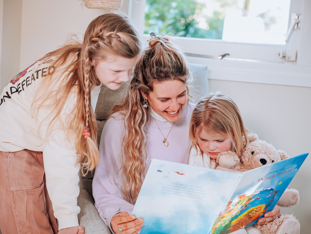 An au pair reads a book to her two host children.