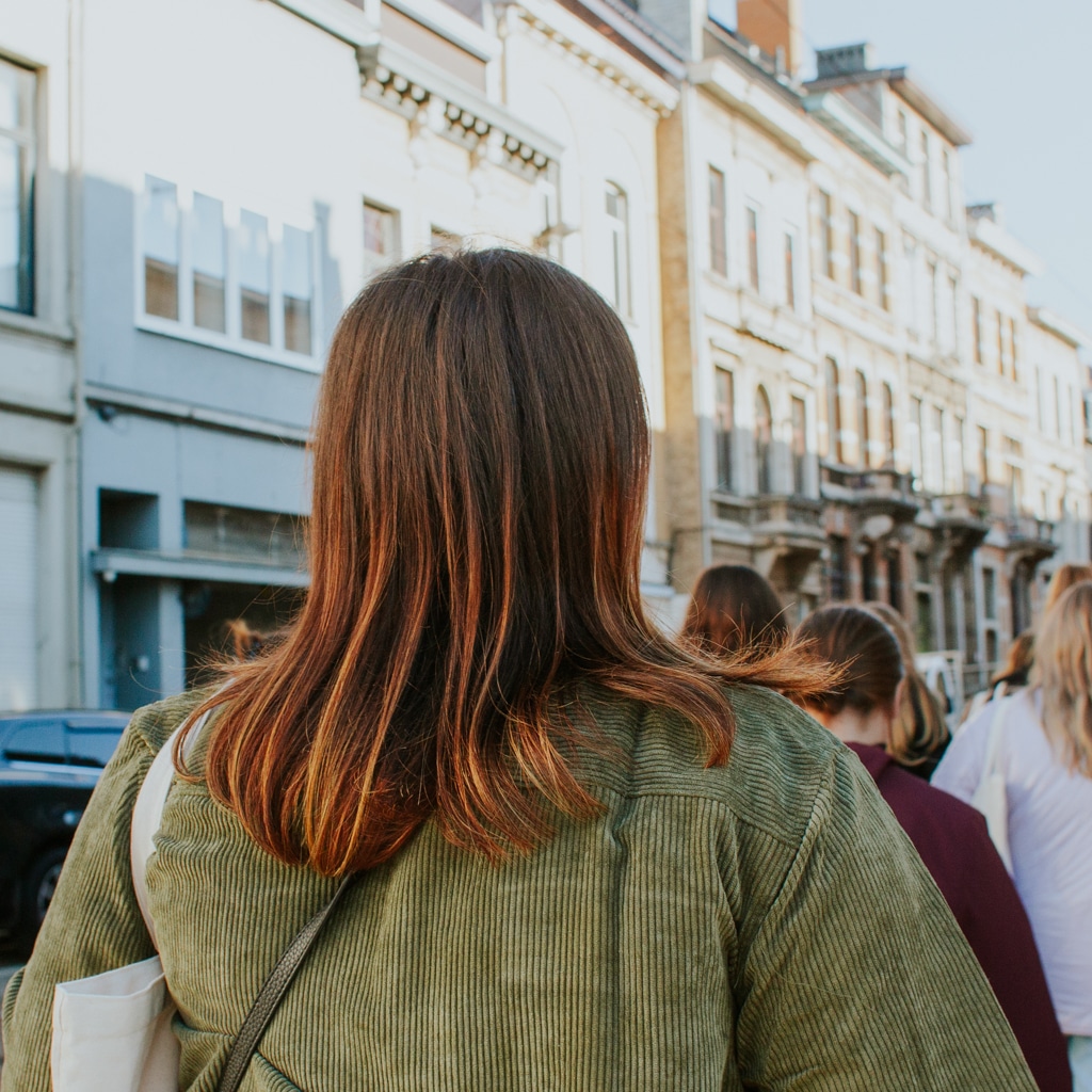 A women walks down a cute street in Antwerp in the morning sunshine.