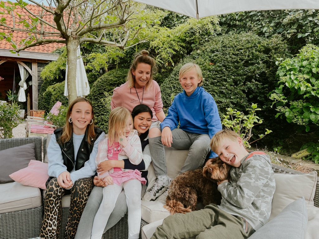 A host family and their au pair sit together outside in the back garden.