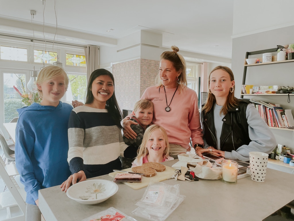 A host family and their au pair stand together around the kitchen counter.