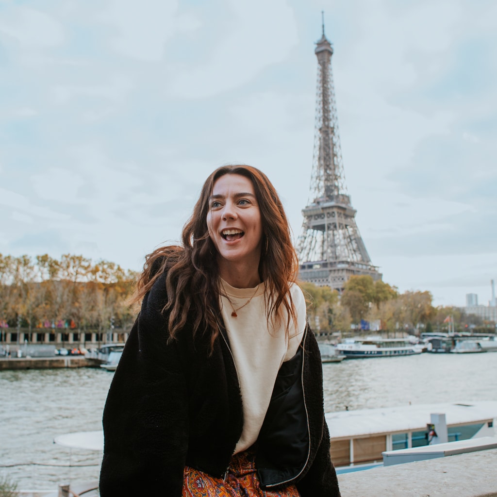 An au pair laughs in front of the Eiffel Tower during her au pair year in France.