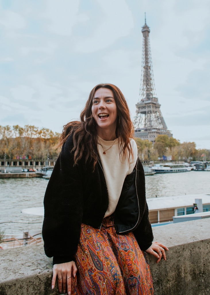 An au pair laughs in front of the Eiffel Tower during her au pair year in France. Conditions to au pair in France.