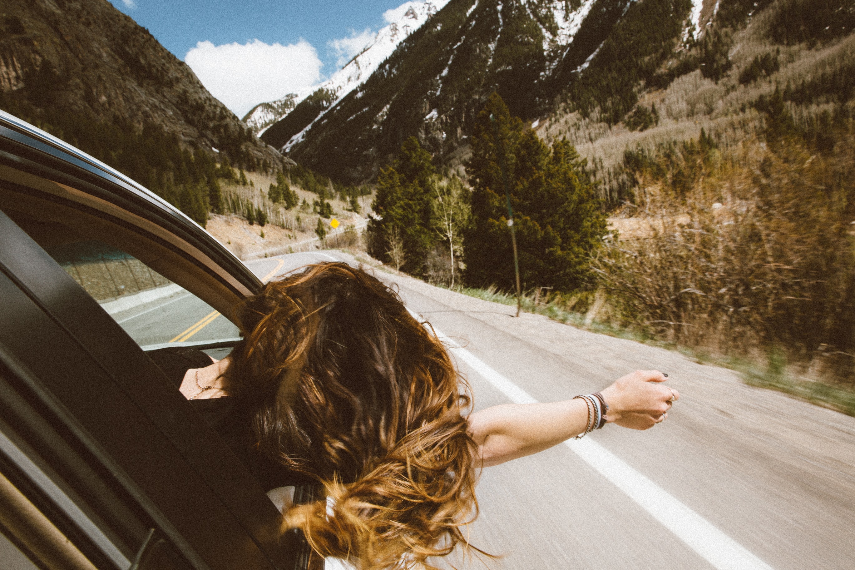 carefree girl hanging out of the window of a driving car looking for an au pair job