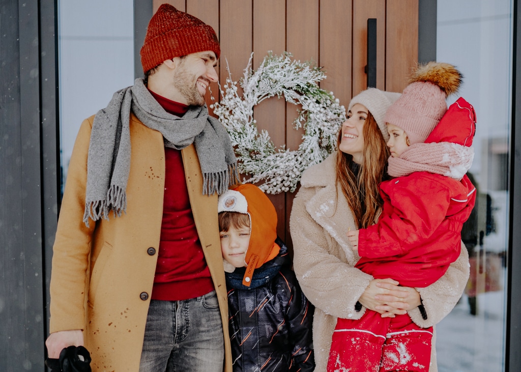 A family stands bundled up in their winter clothes in front of their home in Norway.