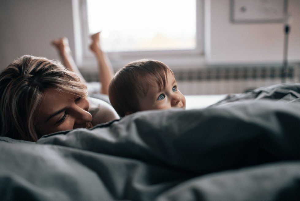 moeder met klein kindje liggen samen op bed 