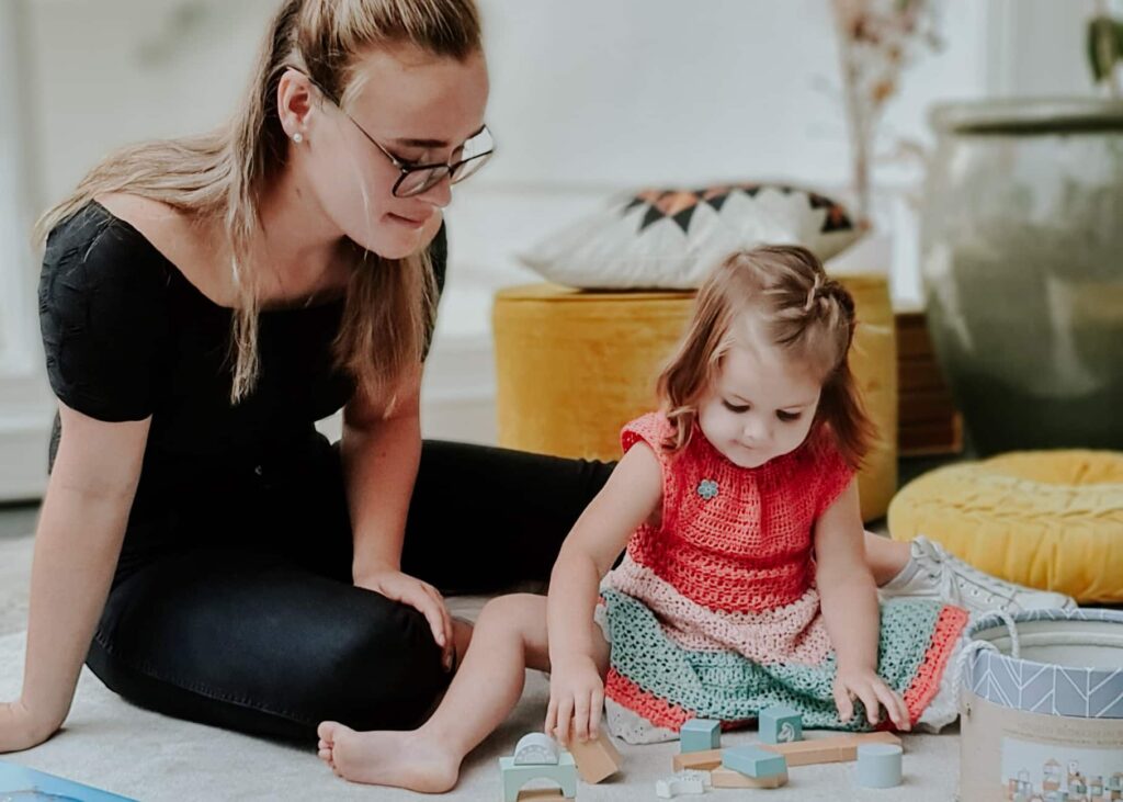 An au pair plays a game with one of her host children in their living room.