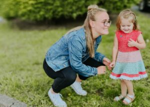 An au pair smiles and holds hands with one of the host children.
