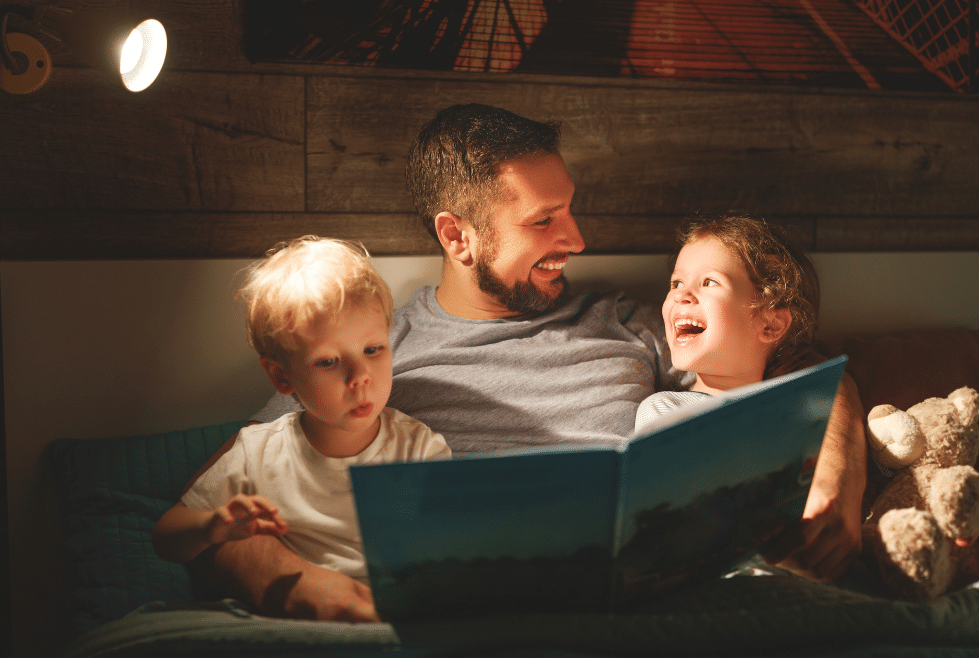 vader met zijn twee kinderen die voor het slapen een boek voorleest als bedritueel