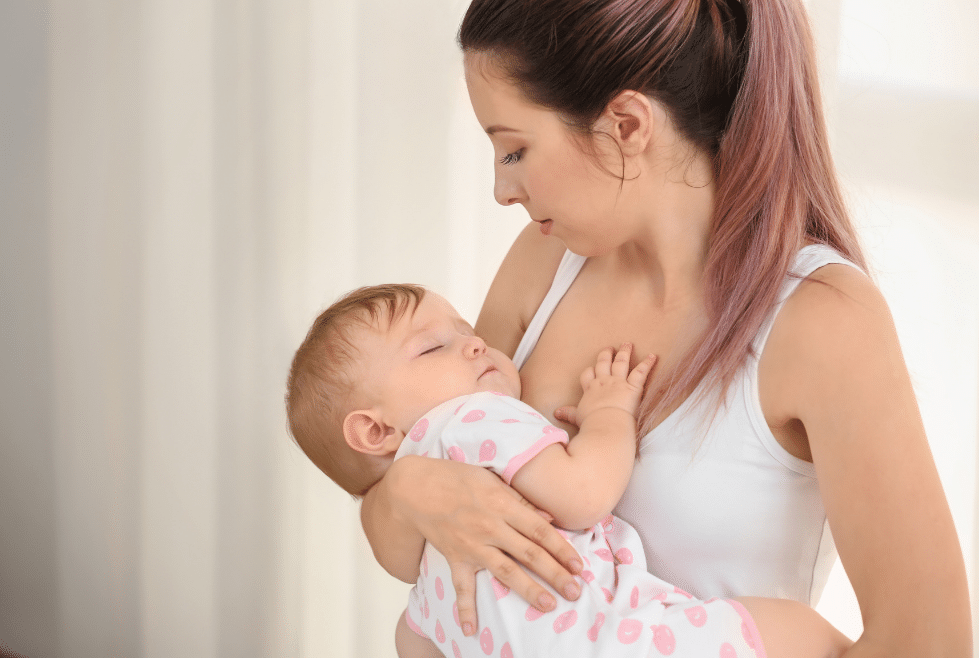 Moeder met slapende baby in haar armen na het toepassen van tips over de slaapcyclus van haar baby 