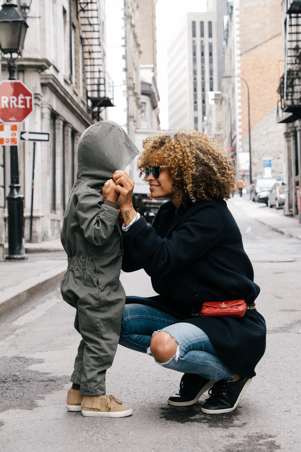 An au pair and her host kids stand in the city together. You can book an au pair easily through the nina.care website or by downloading the app!