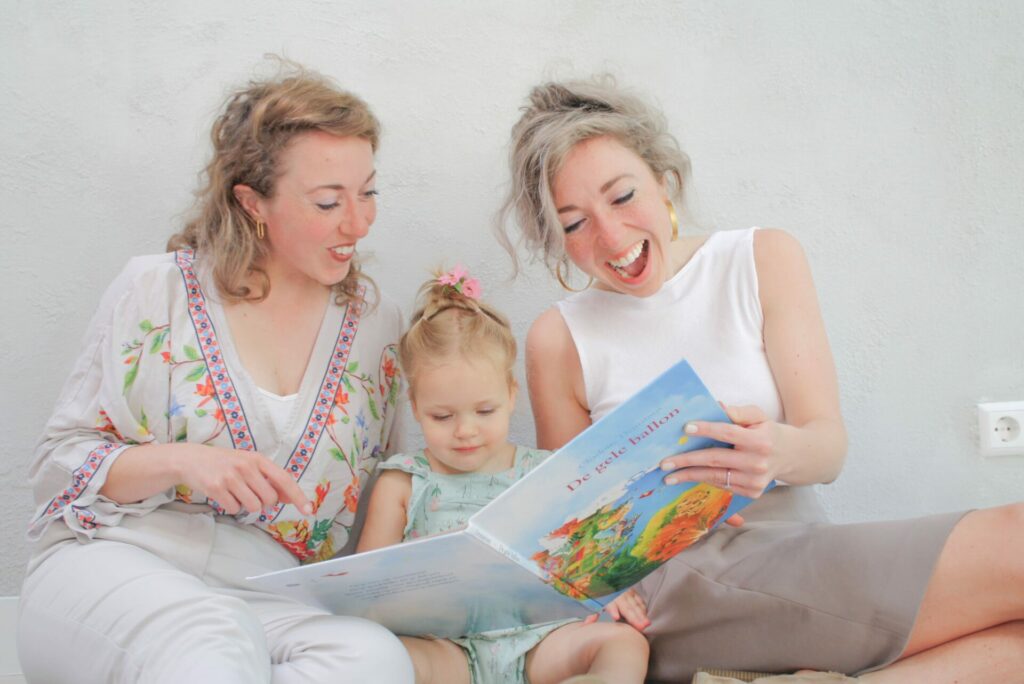 tweeling en eigenaresses van nanny nina, lyla en jasmijn kok, samen met oppaskindjes uit een boek aan het lezen terwijl ze lachen