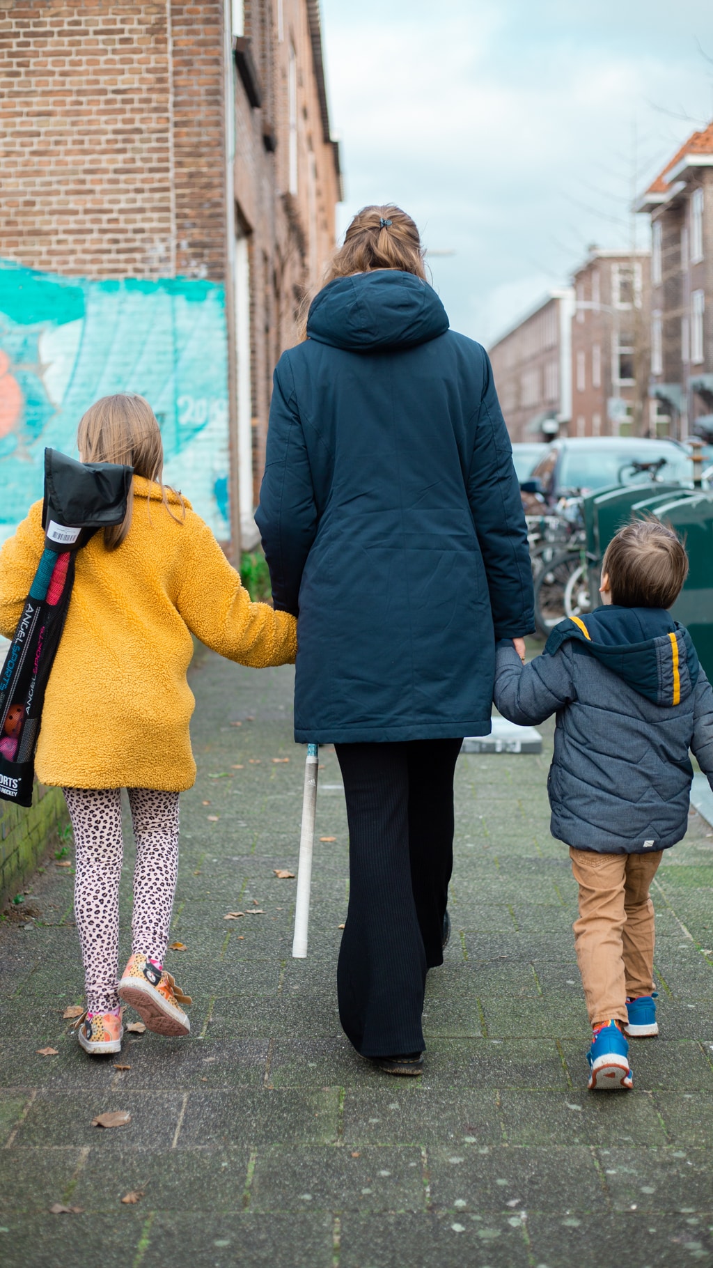 For host families, the initial upfront cost of getting an au pair can vary. In this image an au pair holds hands with her host children as they walk to the park.