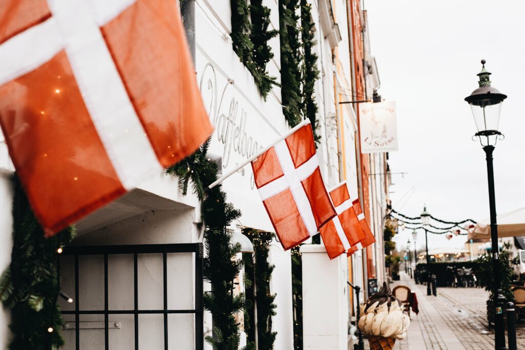 Danish flags and strands of garland and lights in front of a shop front. 