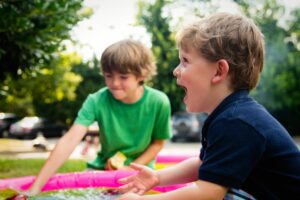 twee jongens die in de zomer buitenspelen met water