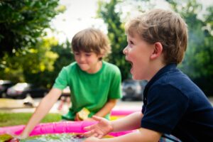 twee jongens die in de zomer buitenspelen met water 