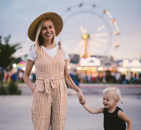 au pair står i hatt för mässan med ett barn bredvid sig