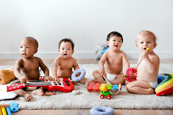 baby's naast elkaar op een rijtje met speelgoed instrumenten