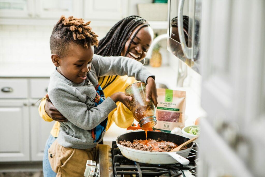 kindje met zijn oppas in de keuken verschillende recepten aan het koken 