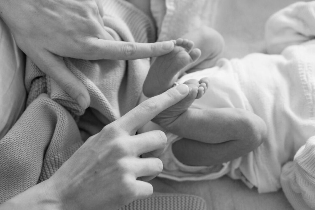 zwart wit foto van moeder die legt haar vingers op de voeten van haar pasgeboren kindje tijdens zwangerschapsverlof