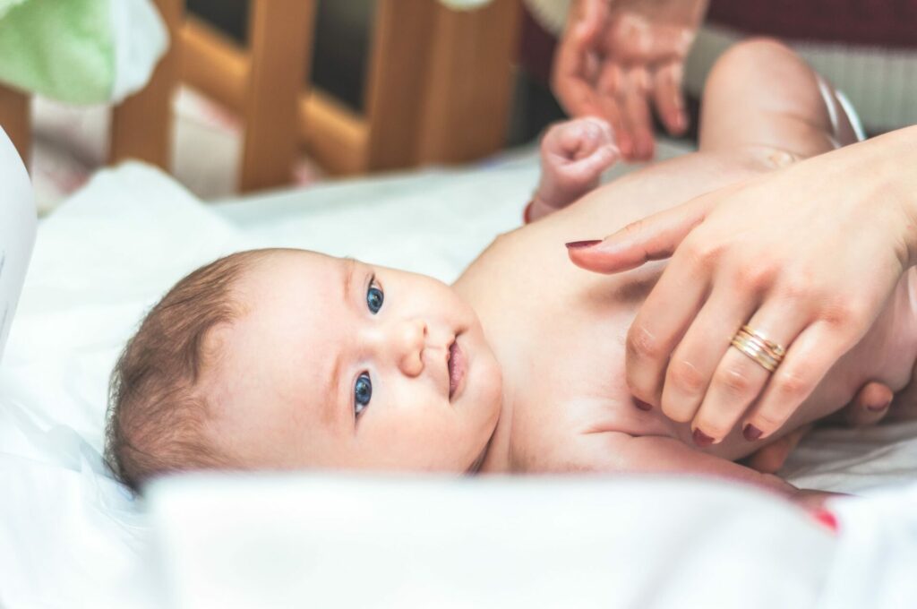 pasgeboren baby die op een kleed ligt en door zijn moeder wordt aangekleed tijdens de kraamtijd