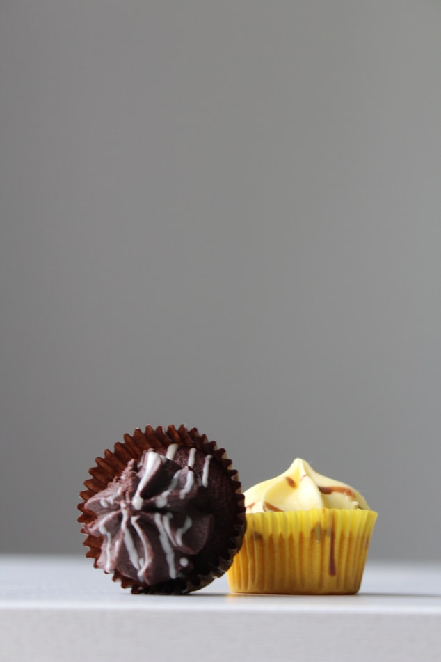een chocolade en een vanille cupcake naast elkaar