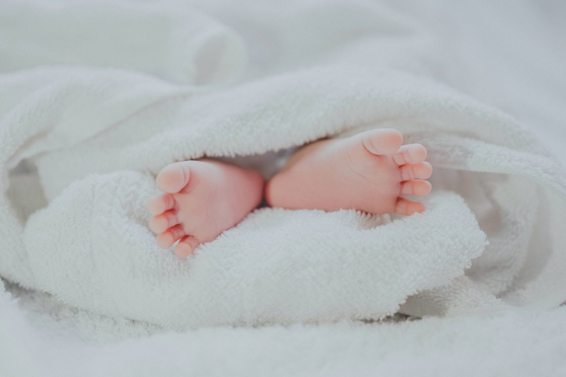 voetjes van een pasgeboren bij op een bed in een wit kleed gewikkeld tijden zwangerschapsverlof
