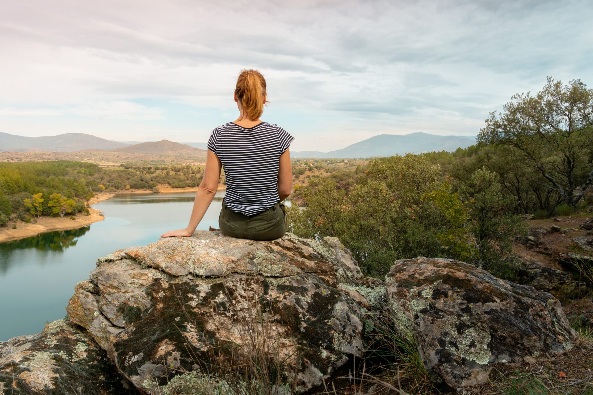 au pair in spain sitting on a rock looking out on a lake