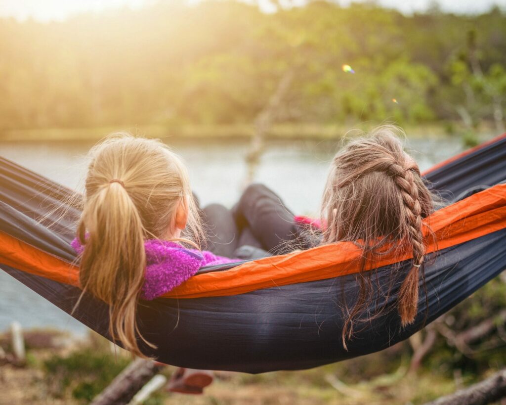 twee kinderen die samen in een hangmat zitten en aan het ontspannen zijn