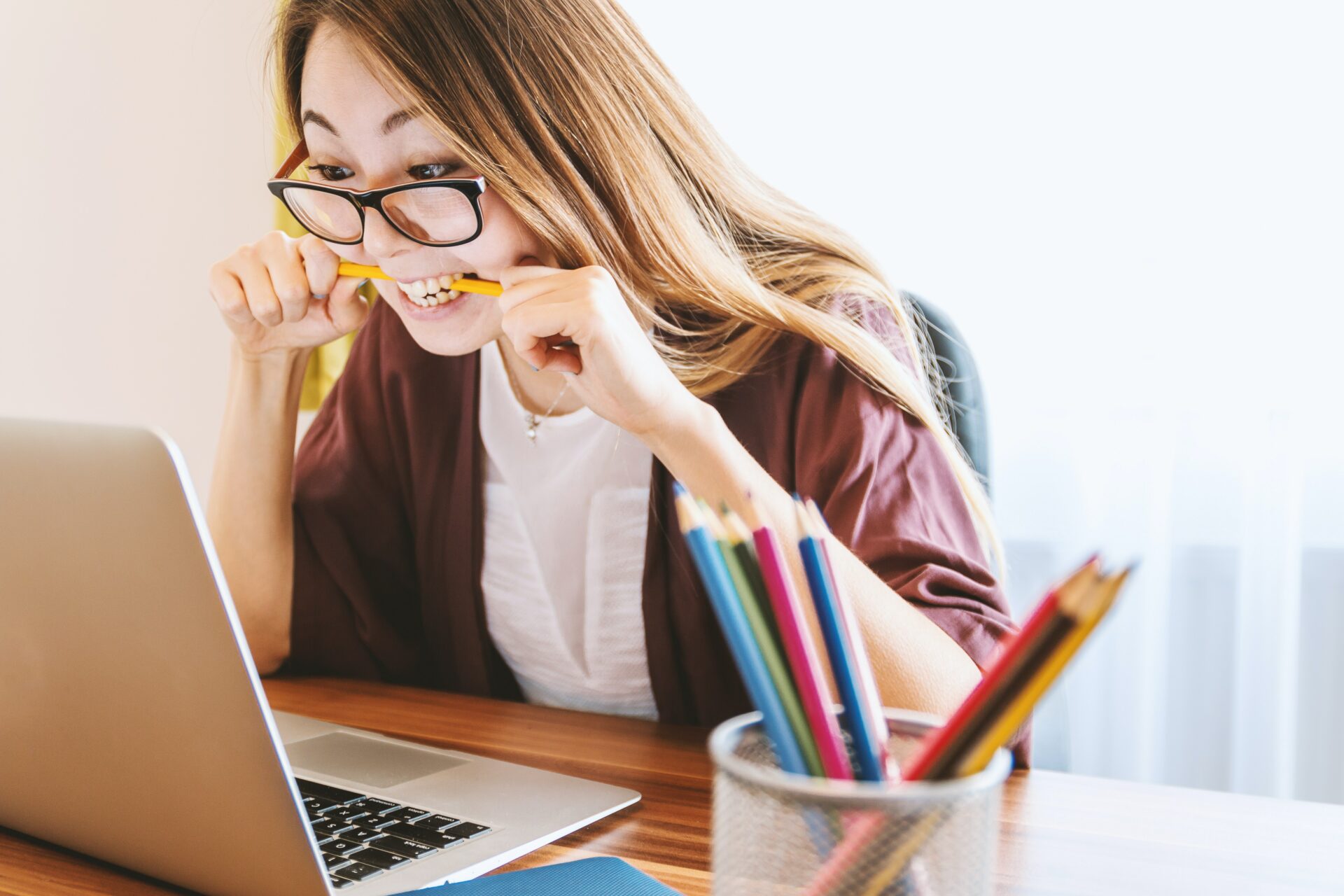 deze au pair raakt gefrustreerd door het aanvragen van de benodigde au pair verzekering en ze zit achter een laptop op wat potloden te kauwen terwijl ze een geïrriteerd gezicht trekt