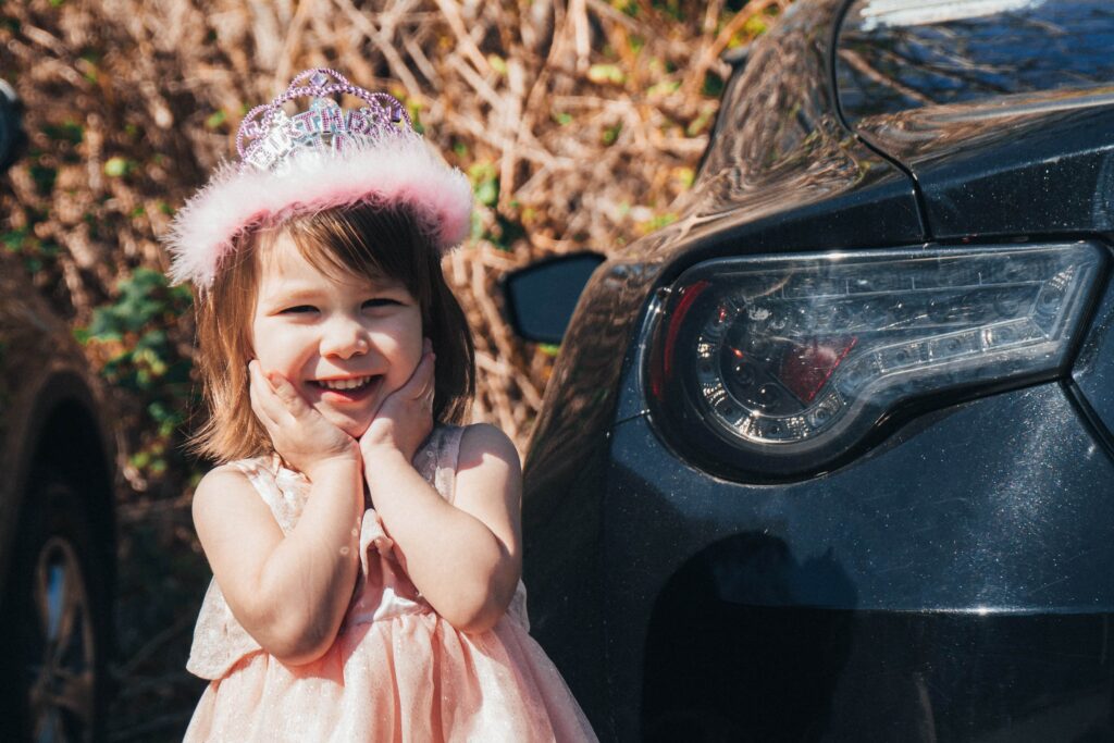 little girl in front of a car