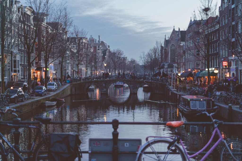 amsterdam canals with bicycles and cars, and walking people travel tips