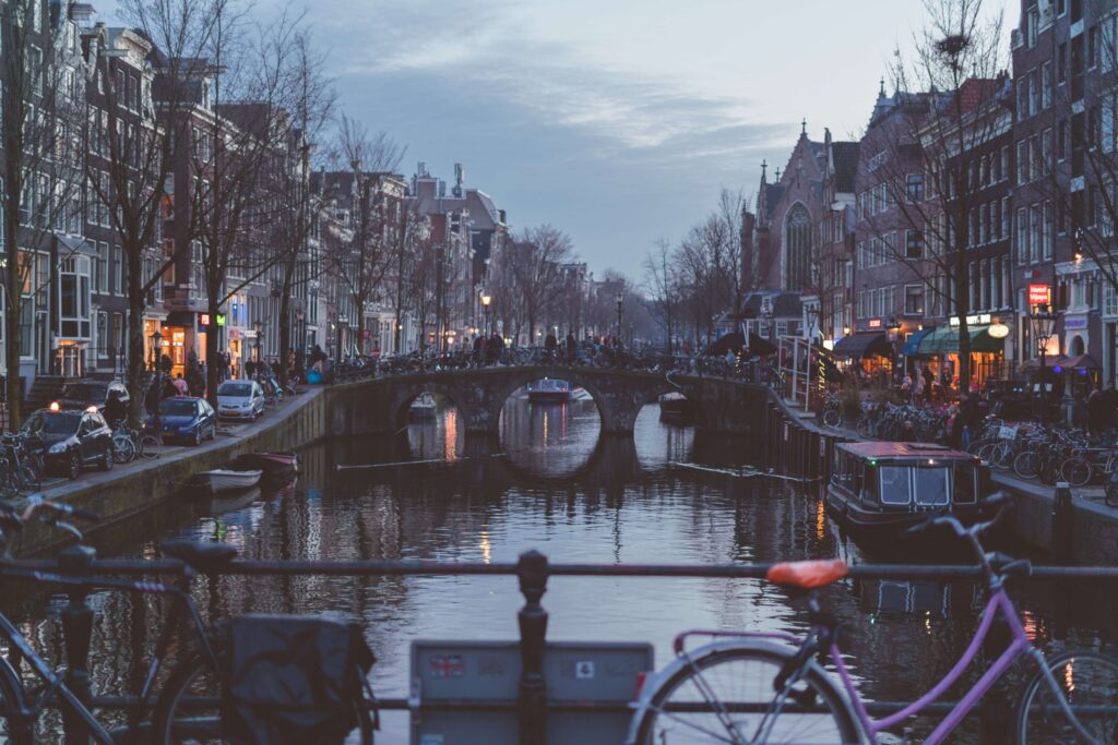 Amsterdam canals with bicycles and cars, and walking people travel tips
