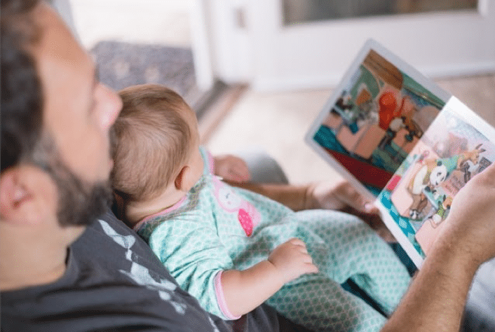 vader die een boekje voorleest aan een baby. belangrijke tip voor ouders, speel mee