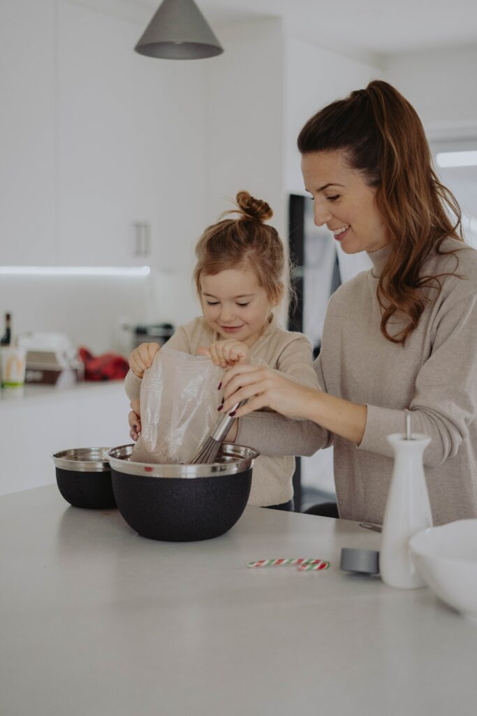 oppas samen met haar oppaskindje aan het bakken in de keuken tijdens het oppassen 