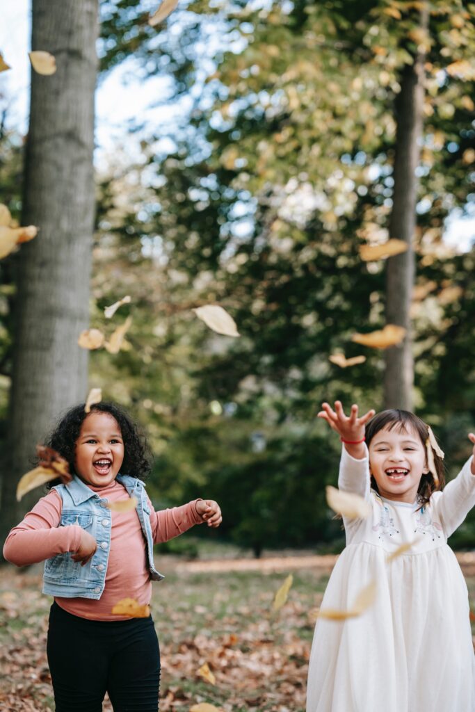 kinder spielen mit blättern im wald bei waldspielen