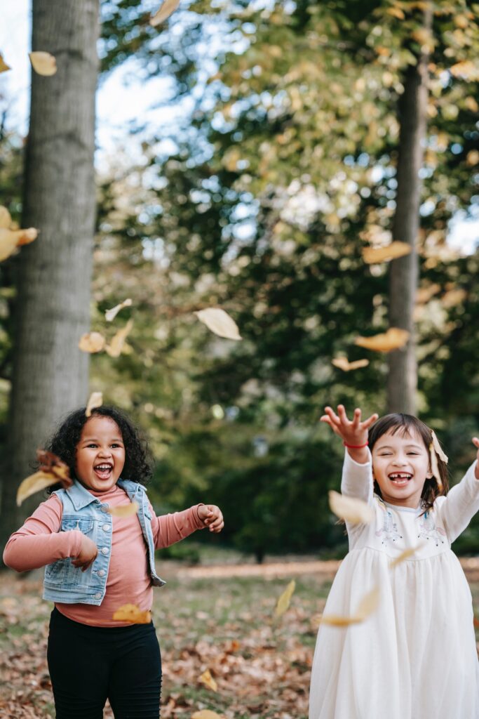 kinderen spelen in het bos met bladeren tijdens bosspelletjes