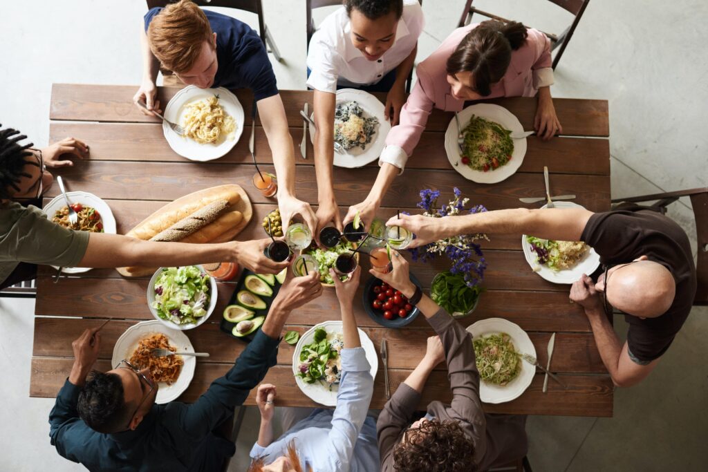 een tafel met eten erop en mensen eromheen die prosten voor vertrek au pair