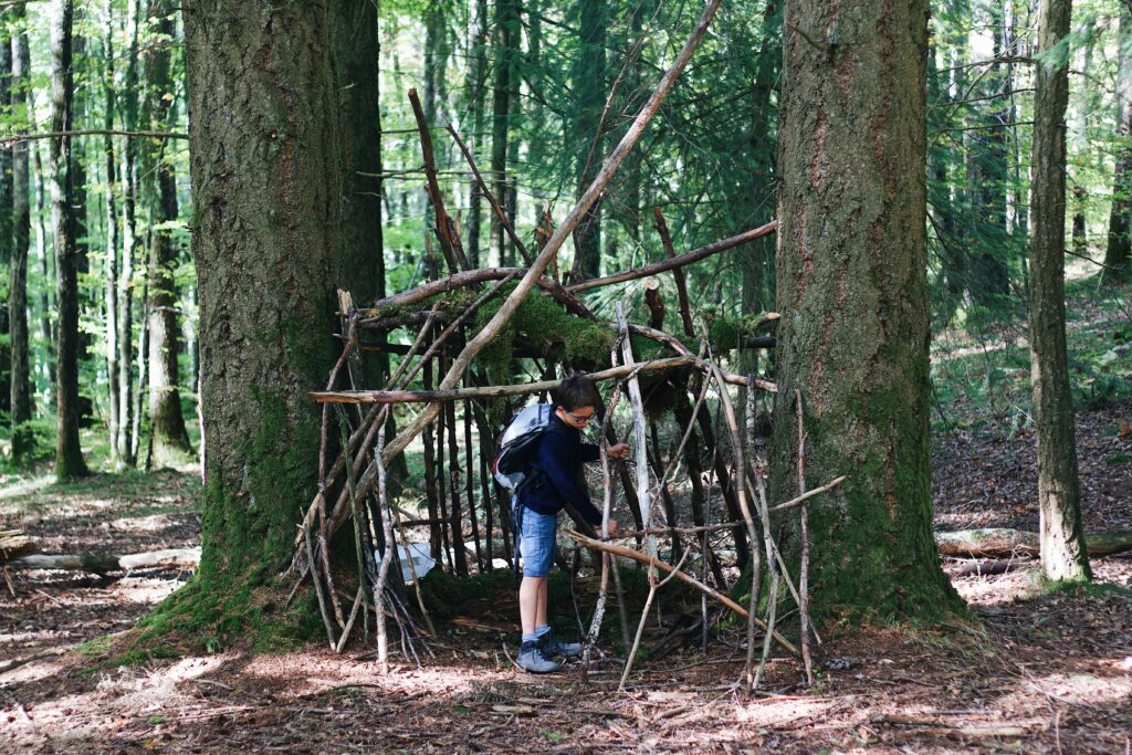 het bosspelletjes die op de foto te zien is is huttenbouwen. er staat een jongentje hutten te bouwen