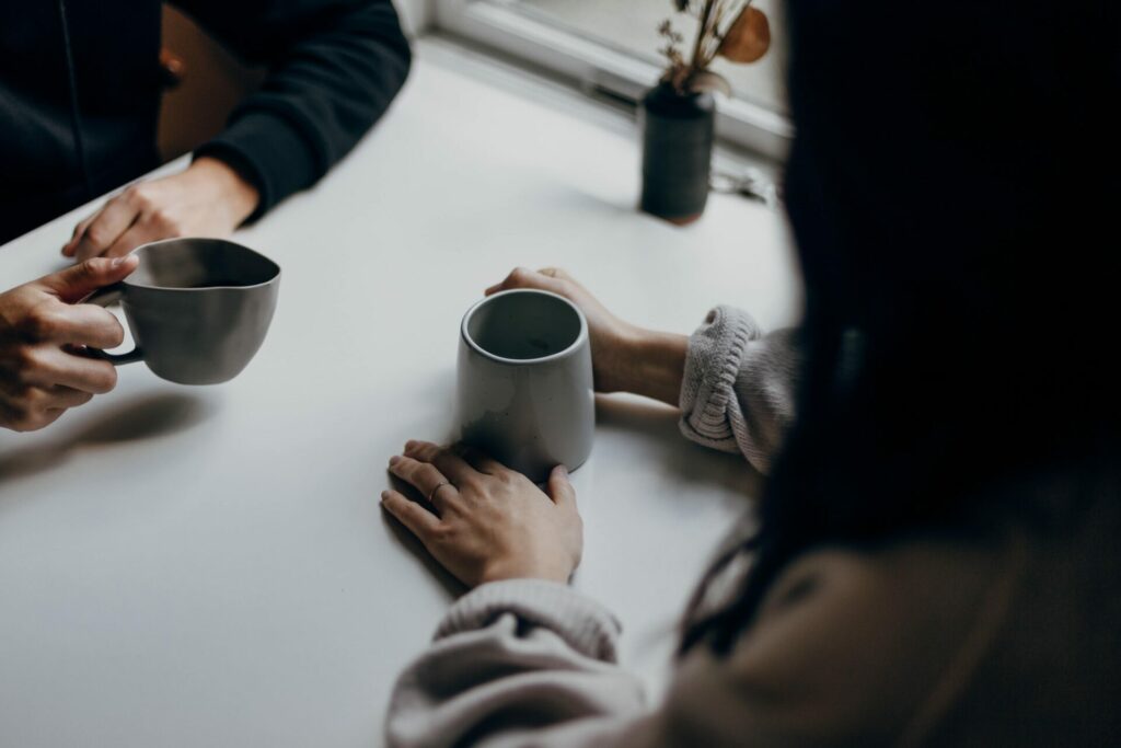 twee mensen drinken koffie en zitten aan tafel om een moeilijk gesprek te voeren 