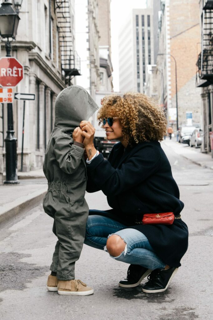 au pair verzekering au pair zit op haar hurken met lief kindje met capuchon ergens in een grote stad