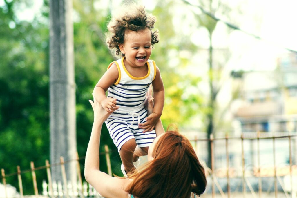 au pair die haar host kind in de lucht houdt. het kindje lacht