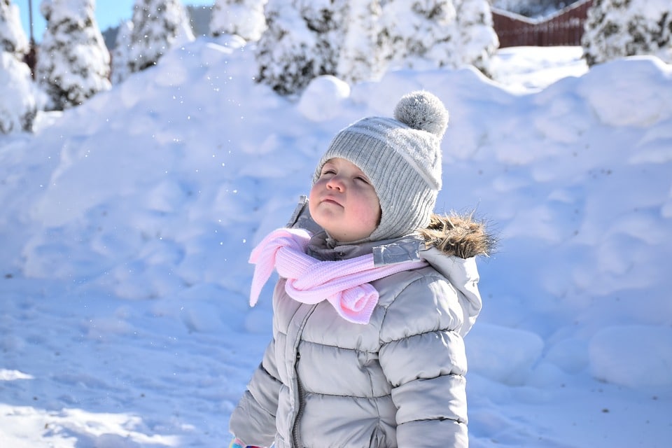 Niño jugando en la nieve en invierno