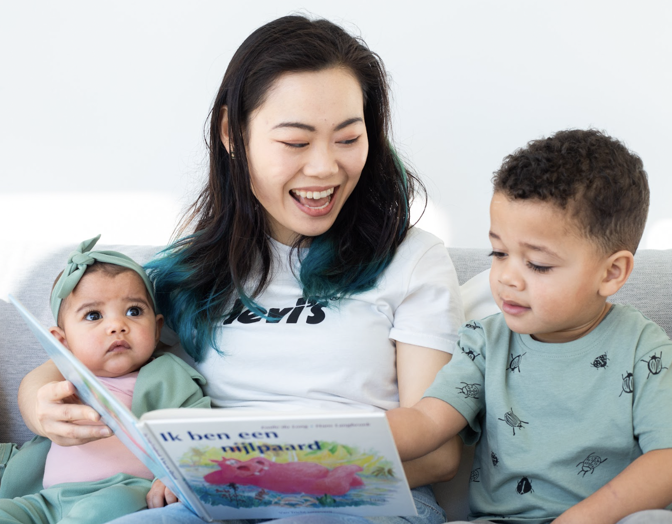 Joyce sittin on the couch with two children reading a book