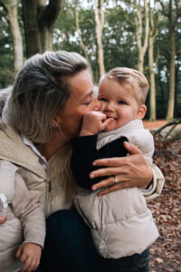 mother daphne talks about hosting an au pair while in the woods playing and kissing her little boy on the cheek