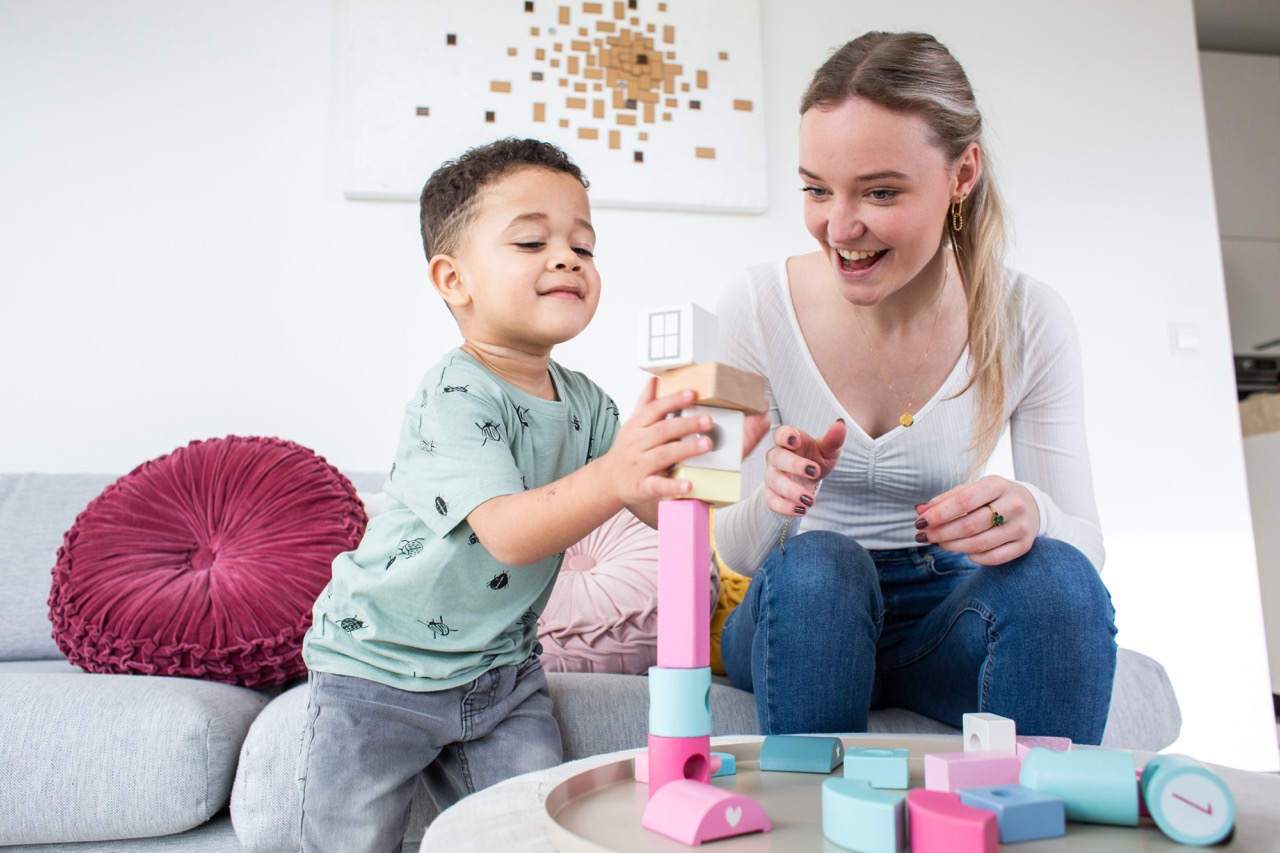 een kind bouwt een toren van blokken met au pair
